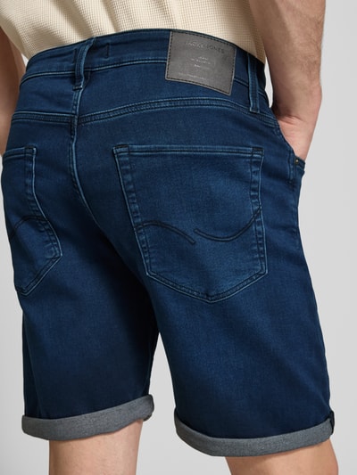 Männermodel trägt Jeansshorts mit Umschlag Modell 'RICK' von Jack & Jones aus Baumwoll-Mix mit Woll-Anteil, Regular-Fit, Eingrifftaschen, Rückansicht Ganzkörperansicht. Bundweite 42 cm, Innenbeinlänge 21 cm, Größe M.