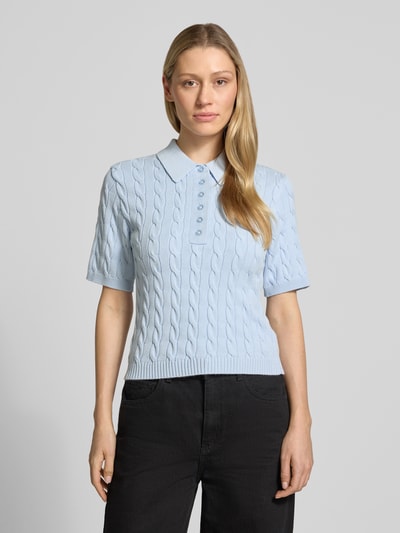 Frauenmodel trägt hellblaues Slim Fit Poloshirt aus Viskose-Mix Modell 'Thilla' von Gestuz mit Strick-Optik und Polokragen, Ganzkörperansicht von vorne. Damen Poloshirt, Halbarm, elastische Abschlüsse, Rückenlänge 51 cm, Ärmellänge 25 cm.