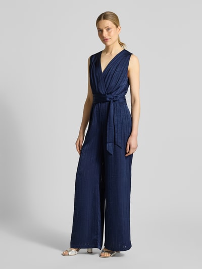Frauenmodel trägt Jumpsuit mit Strukturmuster Modell 'Telma' von SUNCOO PARIS in Dunkelblau, Taillierte Passform, V-Ausschnitt, Ärmelloses-Design, abnehmbares Stoffband, Ganzkörperansicht von vorne.