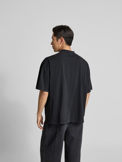 Männermodel trägt Relaxed Fit T-Shirt aus Baumwolle von VETEMENTS in Schwarz mit Destroyed-Look, Ganzkörperansicht Rückansicht.