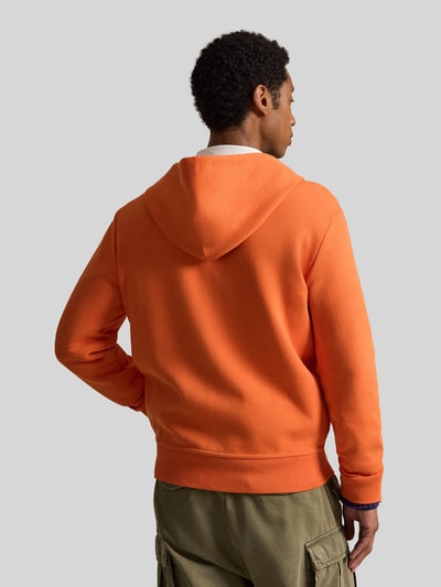 Męski model nosi Regular Fit Sweatjacke aus Baumwoll-Mix von Polo Ralph Lauren, pomarańczowa, proste kształty, tekstura miękka, Ganzkörperansicht Rückansicht.