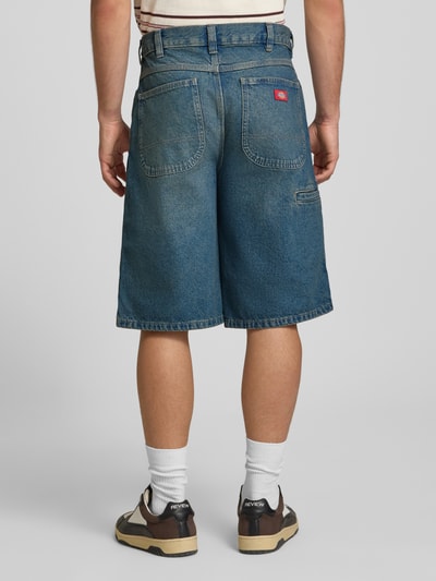 Männermodel trägt Loose Fit Bermudas mit Eingrifftaschen van Dickies, blauw denim, katoen, steekzakken, achterkant, geheel beeld.