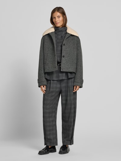 Frauenmodel trägt Jacke mit Kentkragen und Eingrifftaschen von Style Icon Collection in Grau, strukturierte Oberfläche, Ganzkörperansicht von vorne. Gerader Schnitt, Knopfleiste, seitliche Eingrifftaschen, Ärmelriegel mit Knopf, Rückenlänge 54 cm, Schulterbreite 52 cm, Brustweite 50 cm, Ärmellänge 60 cm.