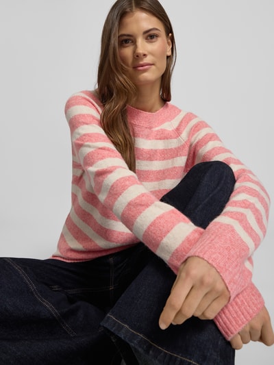 Frauenmodel trägt Regular Fit Strickpullover mit Crew Neck Modell 'DOFFY' von Vero Moda, rosa-weiß gestreift, Stricktextur, Nahaufnahme Oberkörper.