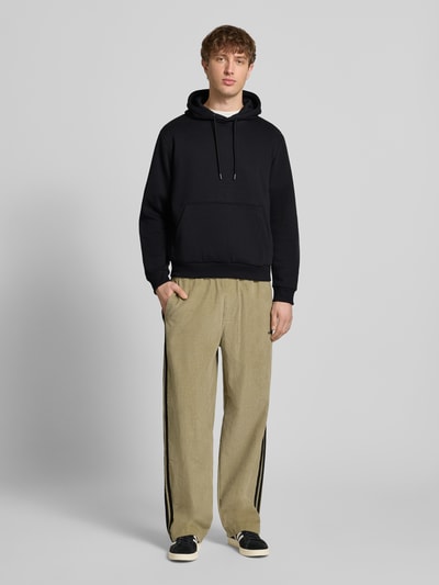 Männermodel trägt Hoodie mit Kapuze Modell 'BRADLEY' von Jack & Jones, schwarz, lockerer Schnitt, Baumwoll-Mix, Ganzkörperansicht von vorne.
