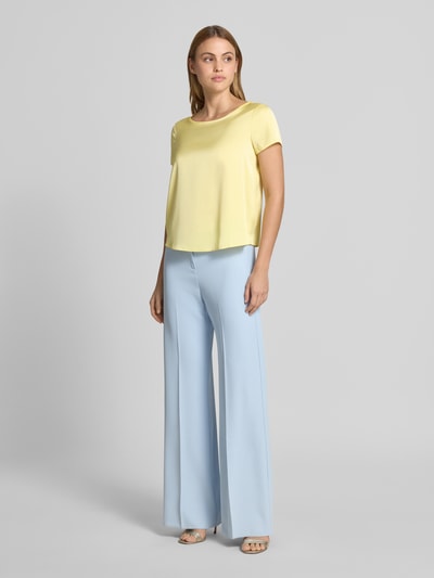 Frauenmodel trägt Blusenshirt mit Rundhalsausschnitt und abgerundetem Saum von Rinascimento, gelb, lockerer Schnitt, Material-Mix, Ganzkörperansicht von vorne.