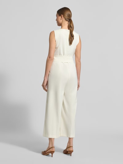 Frauenmodel trägt Jumpsuit mit Bindegürtel von Betty Barclay aus cremefarbenem Material-Mix mit Stretch-Anteil, weite Beine, Rundhalsausschnitt, Ganzkörperansicht Rückansicht. Kontext: Damen Jumpsuit von Betty Barclay, Material-Mix mit Stretch-Anteil, weites Bein, Rundhalsausschnitt, Bindegürtel, Rückenlänge bei Größe 36: 39 cm, Brustweite bei Größe 36: 42 cm, Gesamtlänge bei Größe 36: 132 cm, Innenbeinlänge bei Größe 36: 60 cm.
