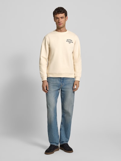 Mannenmodel draagt Sweatshirt mit Label-Print van Scotch & Soda, katoen, regular fit, crèmekleurig, geribde boorden, voorkant, geheel lichaam.
