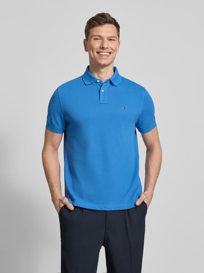 Männermodel trägt Regular Fit Poloshirt aus Baumwoll-Mix von Tommy Hilfiger in Optik: Unifarben mit Logo-Stitching, Polokragen, 2-Knopf-Verschluss, Kurzarm, geschlitztem Rumpfabschluss, Materialverarbeitung: Piqué; Ganzkörperansicht von vorne.