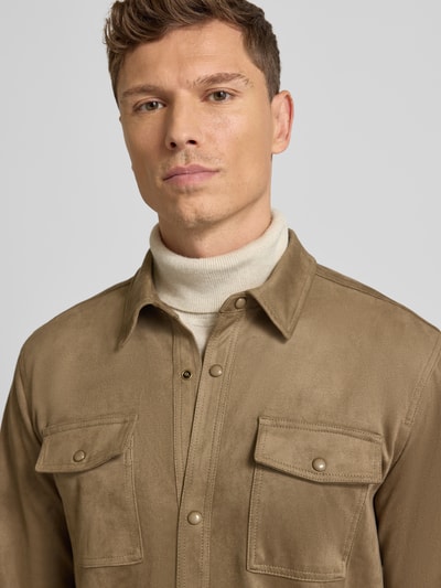 Męski model nosi Hemdjacke mit Kentkragen od Guess, mieszanka materiałów z dodatkiem streczu, krój regular fit, listwa z zatrzaskami, kieszenie zapinane na zatrzaski, kolor beżowy, faktura gładka, widok: zbliżenie na górną część ciała.