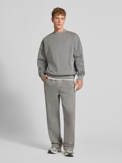 Männermodel trägt Relaxed Fit Sweatshirt aus Baumwoll-Mix von PEGADOR in Grau mit Logo-Stickerei, gerippten Bündchen, Ganzkörperansicht von vorne.