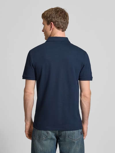 Männermodel trägt Straight Fit Poloshirt mit Label-Stitching von Calvin Klein Jeans, reine Baumwolle, gerippte Ärmelabschlüsse, Ganzkörperansicht Rückansicht.