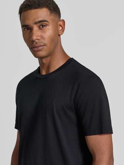 Männermodel trägt schwarzes Regular Fit T-Shirt aus reiner Baumwolle Modell 'JAAMES' von ARMEDANGELS, Nahaufnahme Oberkörper.