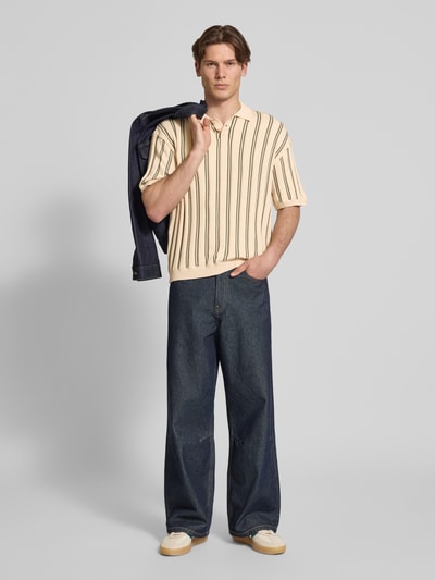 Männermodel trägt Regular Fit Strick-Poloshirt Modell 'POUL' von Redefined Rebel aus Baumwoll-Mix mit Knopfleiste, Rückenlänge 66 cm, Farbkontrast-Streifen, weiche Textur, Ganzkörperansicht von vorne.