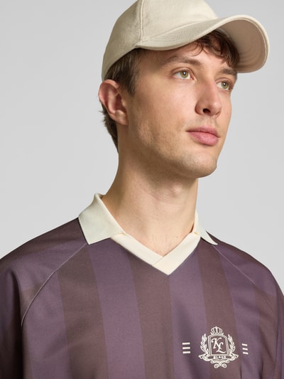 Männermodel trägt Loose Fit Poloshirt mit Motiv-Print Modell 'ZIDAN' von Only & Sons, gestreift, V-Ausschnitt, Nahaufnahme Oberkörper.
