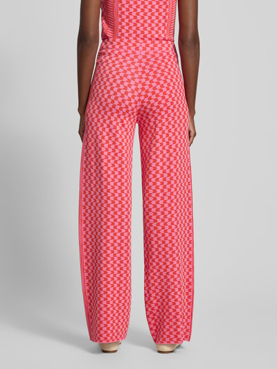 Frauenmodel trägt Flared-Cut Hose aus Viskose-Mix im Allover-Look Modell 'JONAS' von SUNCOO PARIS in leuchtendem Rot mit geometrischem Muster, elastischer Bund, Damen Hose, Ganzkörperansicht Rückansicht.