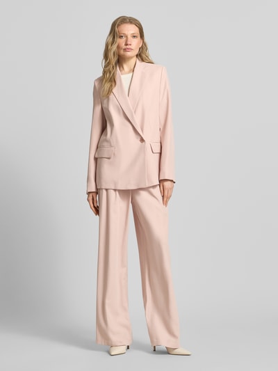Frauenmodel trägt Bundfaltenhose aus Viskose-Mix mit Knopfverschluss von Jake*s Collection in zartem Rosa, Wide Leg, glatte Textur, Ganzkörperansicht von vorne.