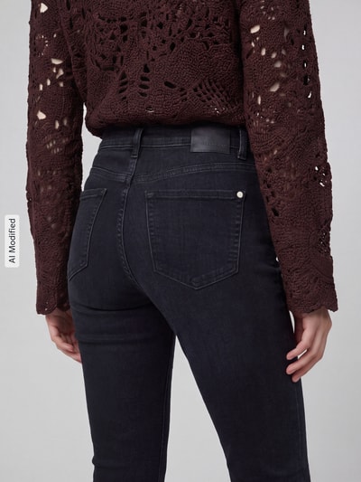Frauenmodel trägt Slim Fit Jeans aus Baumwoll-Mix Modell 'PIPER SHORT' von CAMBIO, dunkles Jeansblau, strukturierte Oberfläche, Damen Slim Fit Jeans Kontext, Nahaufnahme Rückansicht, KI-modifiziertes Bild.