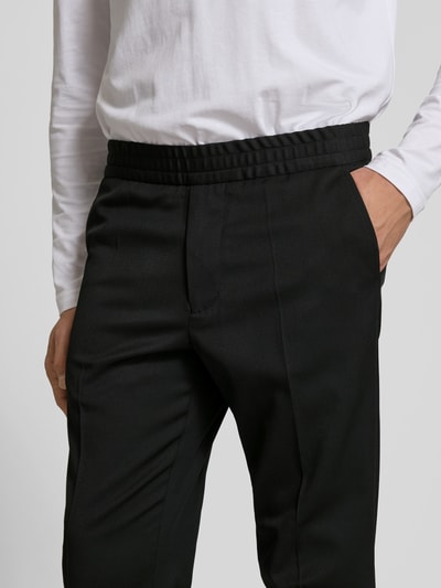 Männermodel trägt Slim Fit Anzughose mit Woll-Anteil von Filippa K, Elastischer-Material-Mix, Eingrifftaschen, Schwarz, Nahaufnahme Oberkörper.