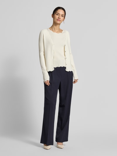 Frauenmodel trägt Strickshirt aus Viskose-Mix mit Rüschenkragen von Christian Berg Woman, tailliert, Halbarm, Wellensaum, Ganzkörperansicht von vorne.