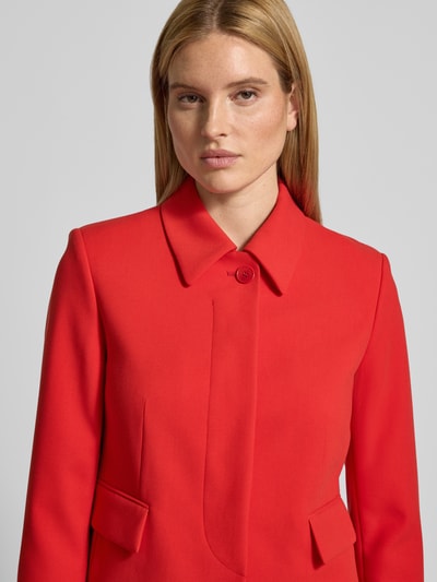 Modelka nosi Żakiet mit Pattentaschen od Windsor, mieszanka materiałów z dodatkiem wiskozy, krój regular fit, kołnierzyk koszulowy, ukryta listwa guzikowa, kieszenie z patką, długość tyłu w rozmiarze 36: 52 cm, szerokość w rozmiarze 36: 48 cm, długość rękawów w rozmiarze 36: 61 cm, intensywnie czerwony kolor, gładka tekstura, prostokątne formy, zbliżenie na górną część ciała, przód