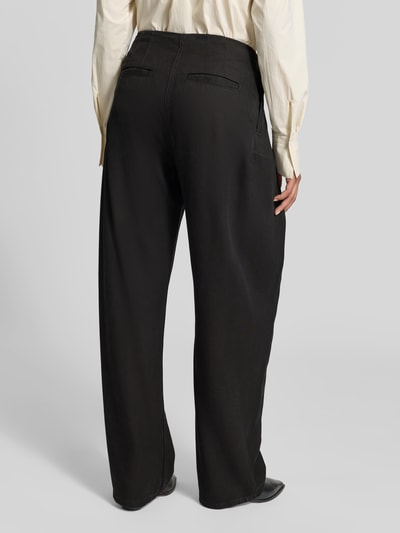 Frauenmodel trägt Wide Fit Jeans aus reinem Lyocell von Iro in Schwarz mit Bundfalten und Gesäßtaschen, Ganzkörperansicht Rückansicht.
