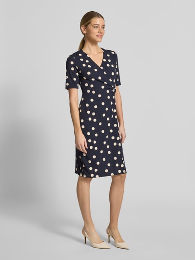 Vrouwenmodel draagt Tailliertes Midikleid in Wickeloptik van s.Oliver BLACK LABEL, donkerblauw met polka dots, o-ring detail, v-hals, korte mouwen, midi-lengte, getailleerde fit, allover patroon, volledige lichaamsaanzicht van voren.