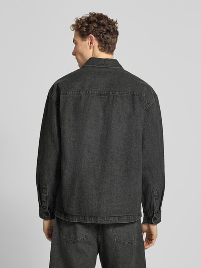 Männermodel trägt Relaxed Fit Hemdjacke mit Brusttasche Modell 'David' von Wood Wood aus dunkelgrauem Baumwoll-Mix mit Kentkragen, Ganzkörperansicht Rückansicht.