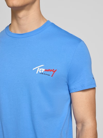 Männermodel trägt Regular Fit T-Shirt aus reiner Baumwolle von Tommy Jeans in Blau, Optik: Unifarben, Label-Print, Logo-Stitching, Rundhals, Kurzarm, Materialverarbeitung: Jersey, Nahaufnahme Oberkörper.