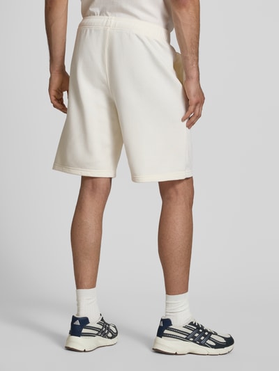 Männermodel trägt Bermudas mit elastischem Bund und Label-Stitching von CHAMPION in Creme, Regular Fit, Baumwoll-Mix, Ganzkörperansicht Rückansicht.