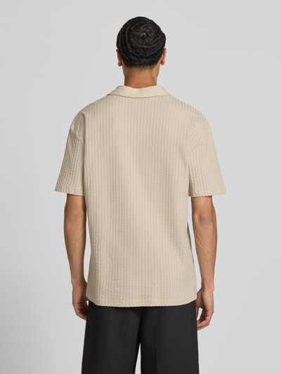 Männermodel trägt Relaxed Fit Poloshirt aus reiner Baumwolle Modell 'AUSTIN' von Only & Sons, Optik: Unifarben, Seersucker, Ganzkörperansicht Rückansicht.