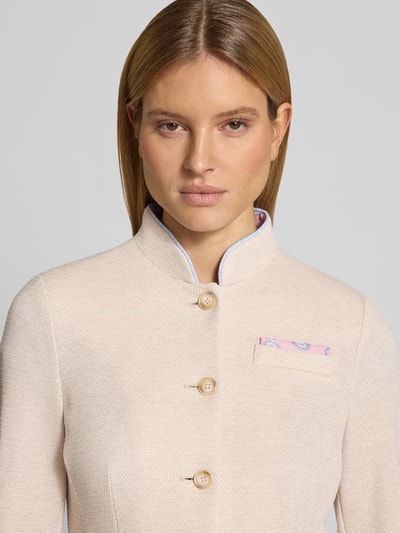 Kobiece model prezentuje żakiet z stójką i brustaszą od WHITE LABEL, mieszanka materiałów z dodatkiem wiskozy, taliowany krój, listwa guzikowa, nakładane wpuszczane kieszenie; długość tyłu 55 cm, szerokość w rozmiarze 36: 44 cm, długość rękawów 62 cm. Zbliżenie na górną część tułowia.