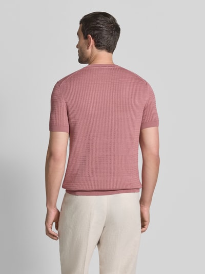 Männermodel trägt Strickshirt mit Strukturmuster Modell 'Elio' von JOOP! COLLECTION aus reiner Baumwolle in Rosa, Ganzkörperansicht Rückansicht.