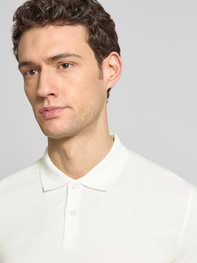 Männermodel trägt Regular Fit Poloshirt aus reiner Baumwolle von Marc O'Polo in Weiß mit Gitterkaro Struktur, Nahaufnahme Oberkörper.