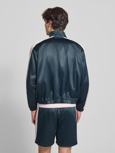 Männermodel trägt Schimmernde Trainingsjacke mit Label-Stitching von BLKVIS in Dunkelgrün mit Stehkragen, Rückenlänge 61 cm, Ganzkörperansicht Rückansicht.