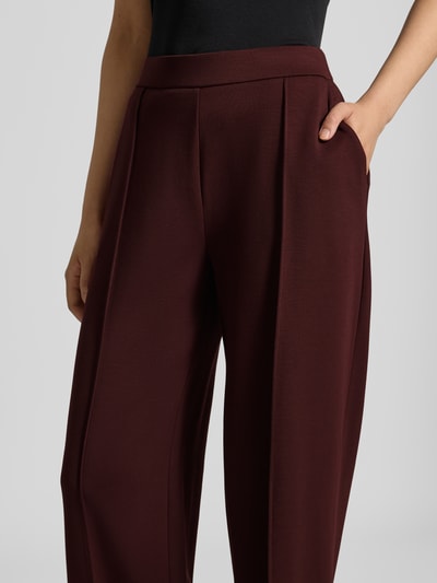 Frauenmodel trägt bordeauxrote Relaxed Fit Weite Hose aus Modal-Mix Modell 'Melane Chill' von OPUS mit glatter Textur, Nahaufnahme Oberkörper, Damen Weite Hose von OPUS.