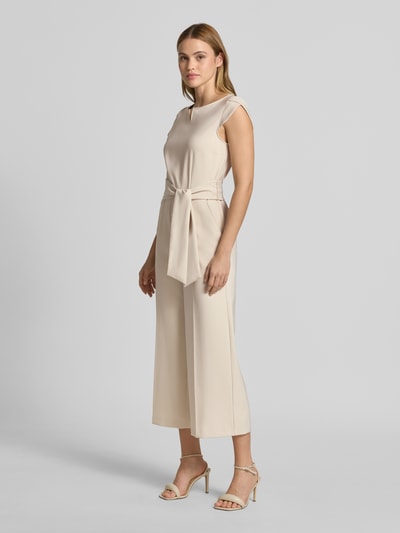 Modelka nosi Regular Fit Jumpsuit mit Bügelfalten von Betty Barclay z elastycznej mieszanki materiałów, kanty, materiałowa tasiemka, jednokolorowy, z krótkim rękawem, całkowita długość 133 cm, szerokość w rozmiarze 36: 47 cm, długość wewnętrzna nogawki 62 cm; całkowita długość 40 cm; widok całej sylwetki z przodu.