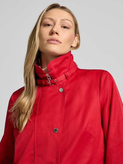 Frauenmodel trägt Trenchcoat mit Stehkragen und Eingrifftaschen von Fuchs Schmitt in Rot, Baumwoll-Mix, Nahaufnahme Oberkörper.