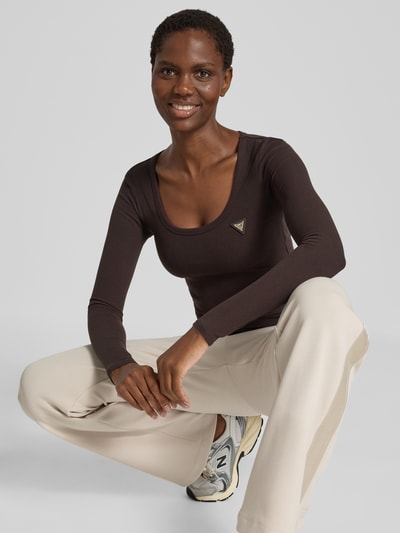 Vrouwenmodel draagt Longsleeve in Ripp-Optik met Label-Applikation Modell 'COLETTE' van GUESS Activewear, slim fit, viscose-elastaanmix, ronde hals, beige broek, neutrale tinten, textuur rib, detail van label op borst, vooraanzicht bovenlichaam