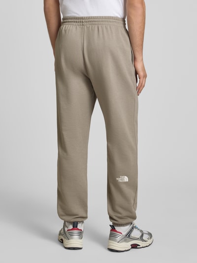 Männermodel trägt Sweatpants mit Logo-Print von The North Face aus Baumwoll-Mix in Slim-Fit mit elastischem Bund, Innenbeinlänge 70 cm, Ganzkörperansicht Rückansicht.
