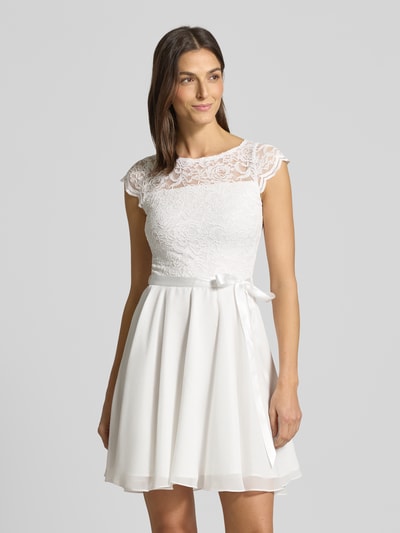 Frauenmodel trägt Cocktailkleid mit Spitzenbesatz und Bindegürtel von SWING in Weiß, A-Linie, Minikleid, Material-Mix mit Stretch-Anteil, Nahaufnahme Oberkörper.