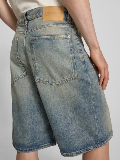 Männermodel trägt Jeansshorts im Used-Look mit Eingrifftaschen von REVIEW, Reine Baumwolle, Relaxed-Fit, Ganzkörperansicht Rückansicht.
