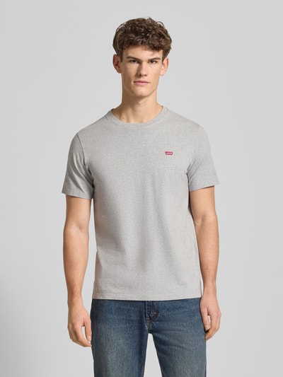 Männermodel trägt T-Shirt mit Label-Detail von Levi's®, reine Baumwolle, Regular-Fit, gerippter Rundhalsausschnitt, Ganzkörperansicht von vorne.