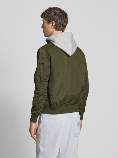 Männermodel trägt Blouson mit Logo-Anhänger Modell 'MA-1 TT' von Alpha Industries in Olivgrün, lockere Passform, Rückenansicht