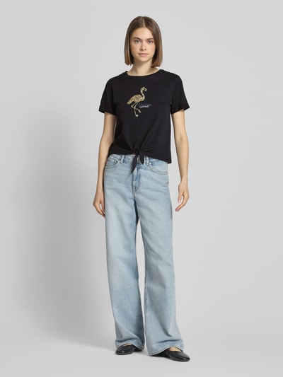 Frauenmodel trägt Regular Fit T-Shirt aus reiner Baumwolle Modell 'DORA LIFE' von Only, schwarz, Pailletten-Applikation, Knotendetail, Rundhals, Kurzarm, Ganzkörperansicht von vorne.