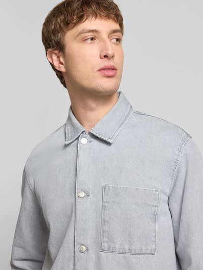 Männermodel trägt Regular Fit Hemdjacke aus reiner Baumwolle von Marc O'Polo Denim in grauer Denim-Optik mit Brusttasche, Nahaufnahme Oberkörper.