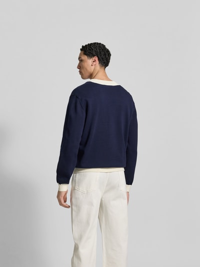 Männermodel trägt Cardigan aus reiner Baumwolle von MAISON KITSUNÉ in Dunkelblau, lockere Passform, Rückansicht Ganzkörperansicht.