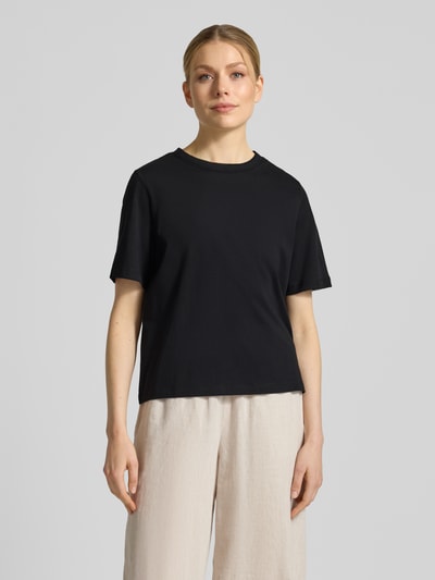 Modelka kobieca nosi Regular Fit T-Shirt aus reiner Baumwolle Modell 'ASSIA' od Selected Femme, czarny jersey, okrągły dekolt, widoczne szwy, przód, ujęcie całej sylwetki.