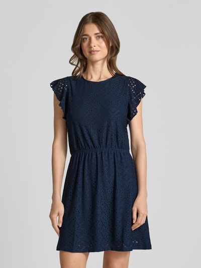 Frauenmodel trägt Tailliertes Sommerkleid mit Lochstickmuster Modell 'TASSA' von Vero Moda in Dunkelblau, Optik: Unifarben, Passform: Tailliert, Mini-Länge, Rundhals-Ausschnitt, Ärmelform: Kurzarm, elastisches Taillenband, Materialverarbeitung: Lochstickmuster, Ganzkörperansicht von vorne.