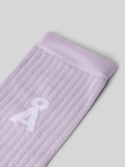 Produktfoto, Socken aus Baumwoll-Mix Modell 'SAAMUS' von ARMEDANGELS in hellem Flieder mit feinem Rippmuster, lila Hintergrund. Damen Socken von ARMEDANGELS.